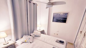 A bedroom with two beds, a ceiling fan, a bedside table with a lamp, and a framed picture on the wall. - Atlantic Terrace. An oasis in the city. (Santa Cruz de Tenerife)