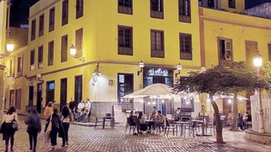 A yellow building with a 'VINTAGE' sign, outdoor seating, and cobblestone pavement. - Atlantic Terrace. An oasis in the city. (Santa Cruz de Tenerife)
