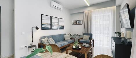 A modern living room with a sofa, armchairs, a coffee table, and a dining table with a plant.