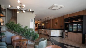 Una moderna hall d'hotel con zone relax, una reception e un bar.