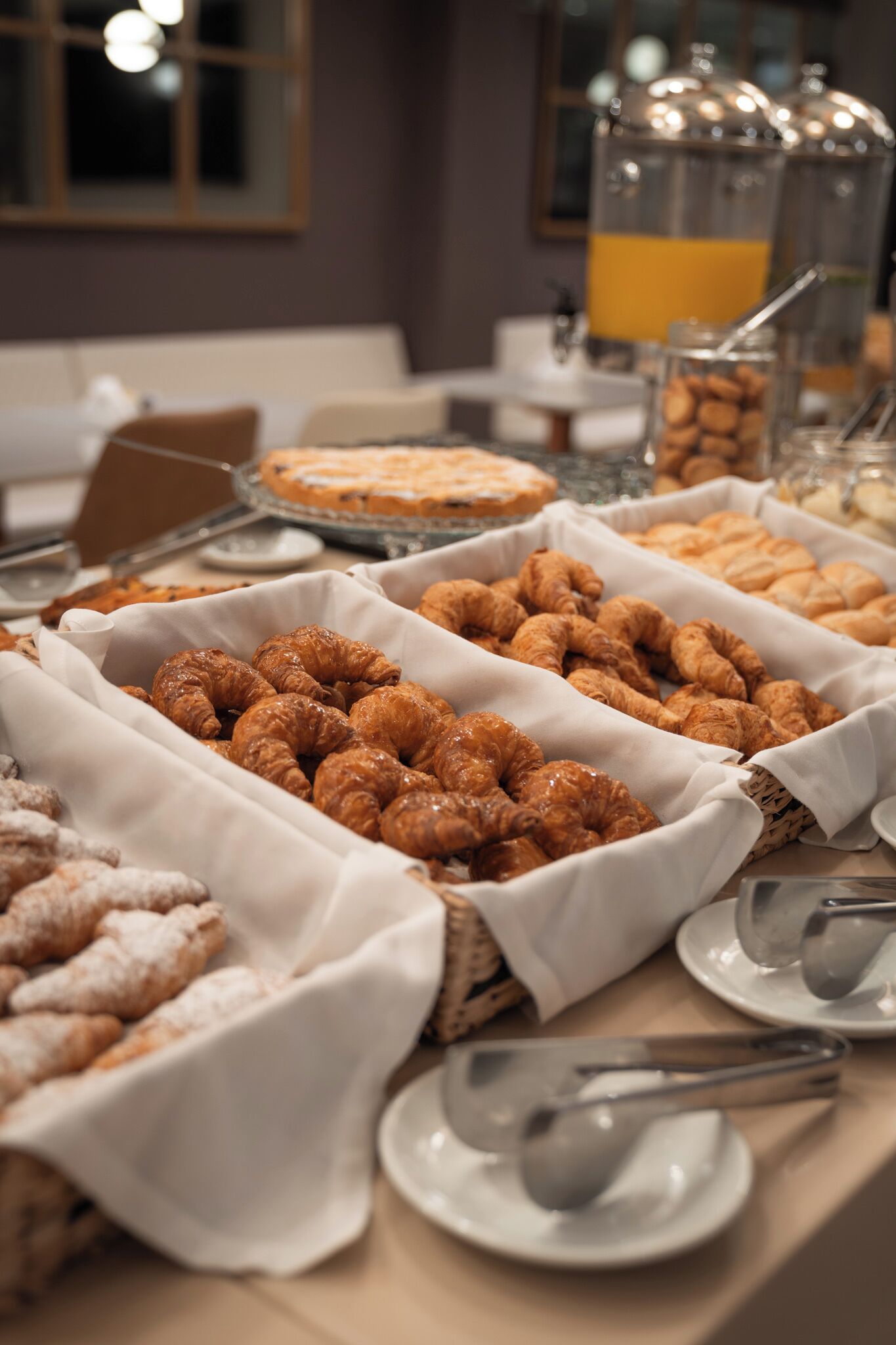 Un bufé con diferentes pasteles y un dispensador de jugo.