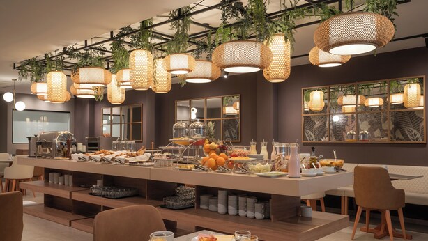 Un buffet per la colazione con diversi cibi, lampade a sospensione in vimini e un design d'interni moderno.