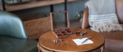 A round wooden table with a chessboard, a pen, and a notepad.
