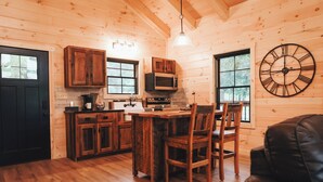 Una cocina tipo cabaña con armarios de madera, una mesa de comedor y un reloj en la pared.