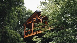 Una cabaña de madera con balcón, rodeada de un bosque frondoso.