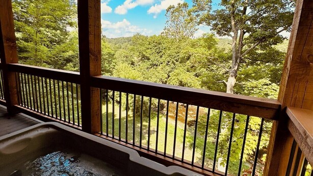 Un jacuzzi en una terraza de madera con vista a un área boscosa.