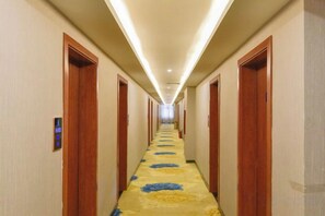 A hotel hallway with doors on both sides, a carpeted floor, and a ceiling light fixture. - Daozhimeng Hotel (Daocheng County)