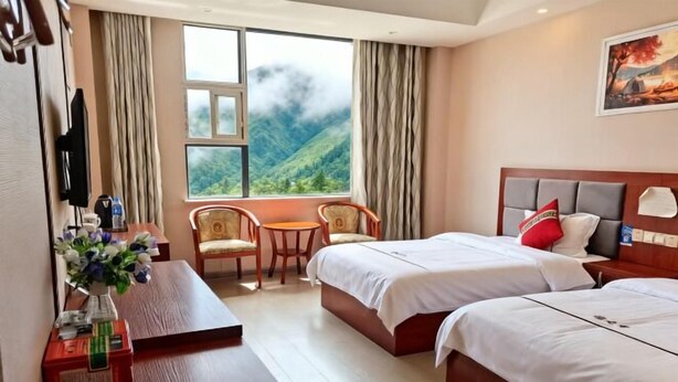 A hotel room with two beds, a desk, a chair, a TV, and a window with a mountain view. - Daozhimeng Hotel (Daocheng County)