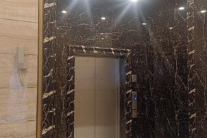 An elevator with a metallic finish, surrounded by walls with a marble-like pattern.
