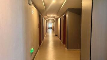 A hotel corridor with doors on both sides, a light switch on the wall, and a ceiling light.