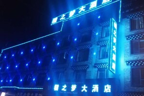 A building with illuminated signage and multiple windows. - Daozhimeng Hotel (Daocheng County)