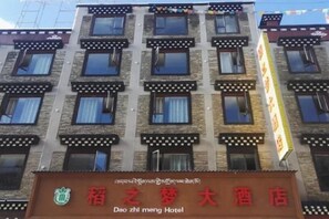A multi-story hotel with a traditional architectural style, featuring a prominent signboard with Chinese characters and a logo. - Daozhimeng Hotel (Daocheng County)