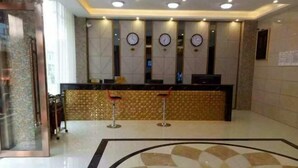 A hotel reception area with a modern design, featuring a reception desk, multiple clocks, and a patterned floor. - Daozhimeng Hotel (Daocheng County)