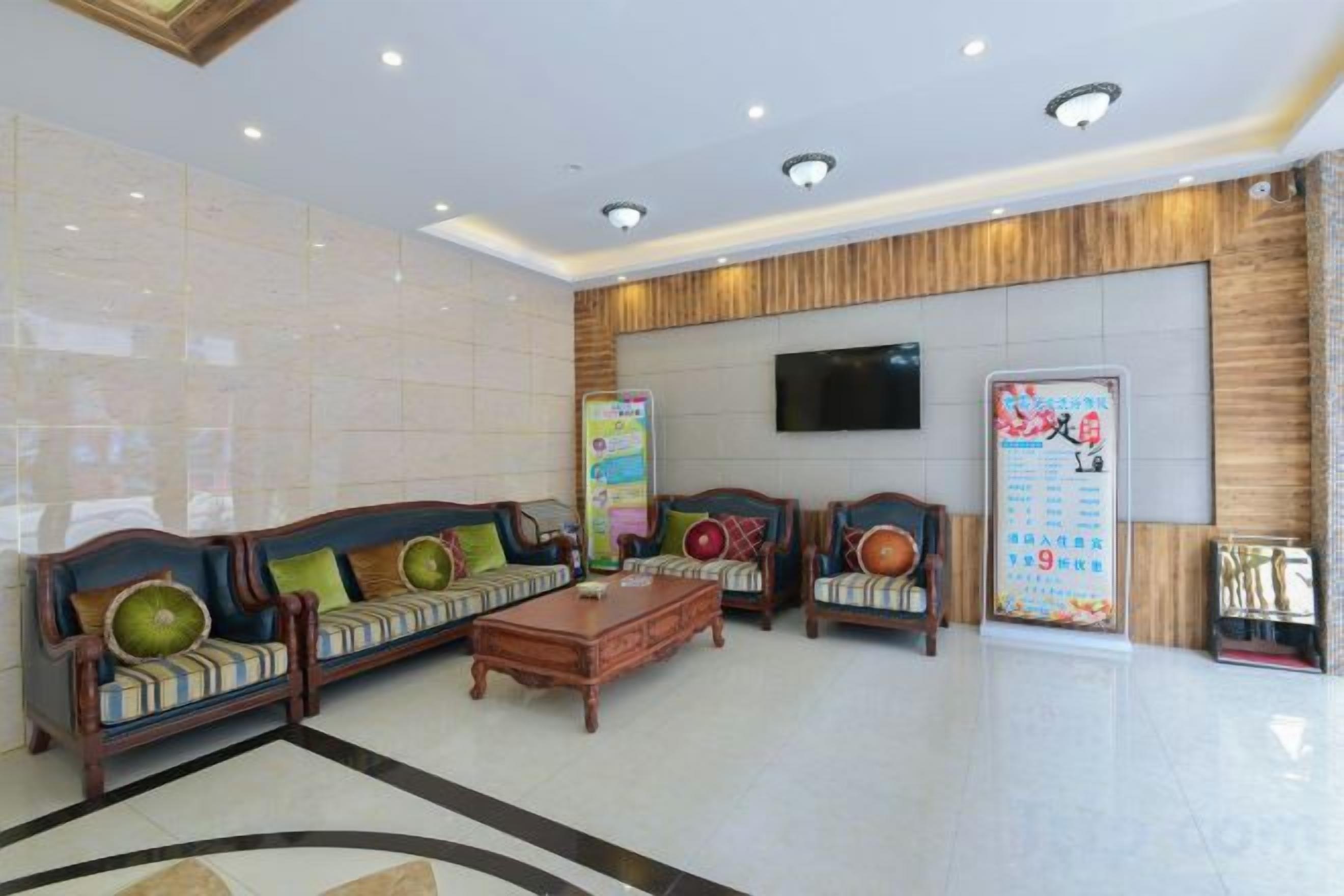 A hotel lobby with a reception desk, sofas, a coffee table, and a television screen.
