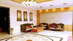 A lobby with two sofas, a coffee table, and three wall-mounted paintings. - Daozhimeng Hotel (Daocheng County)