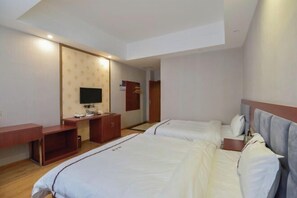 A hotel room with two beds, a TV, a desk, and a wardrobe. - Daozhimeng Hotel (Daocheng County)