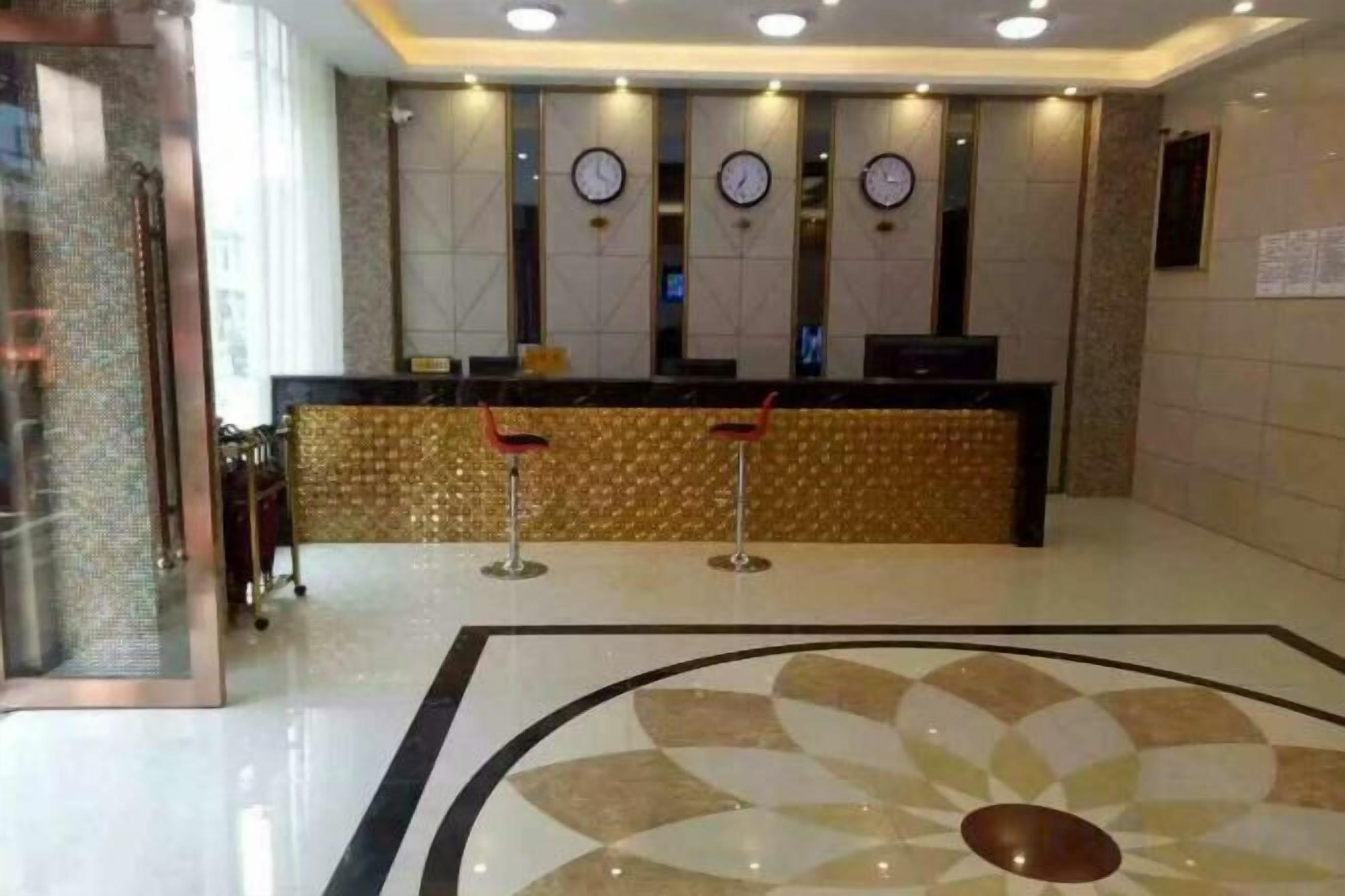 A hotel reception area with a reception desk, clocks, and a patterned floor.