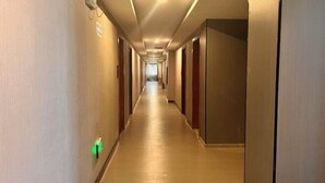 A long, narrow hotel corridor with doors on both sides and a light-colored floor. - Daozhimeng Hotel (Daocheng County)