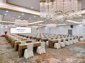 A conference room with rows of tables, a large screen, and chandeliers. - Novotel Wuxi Sanyang Plaza (Wuxi)