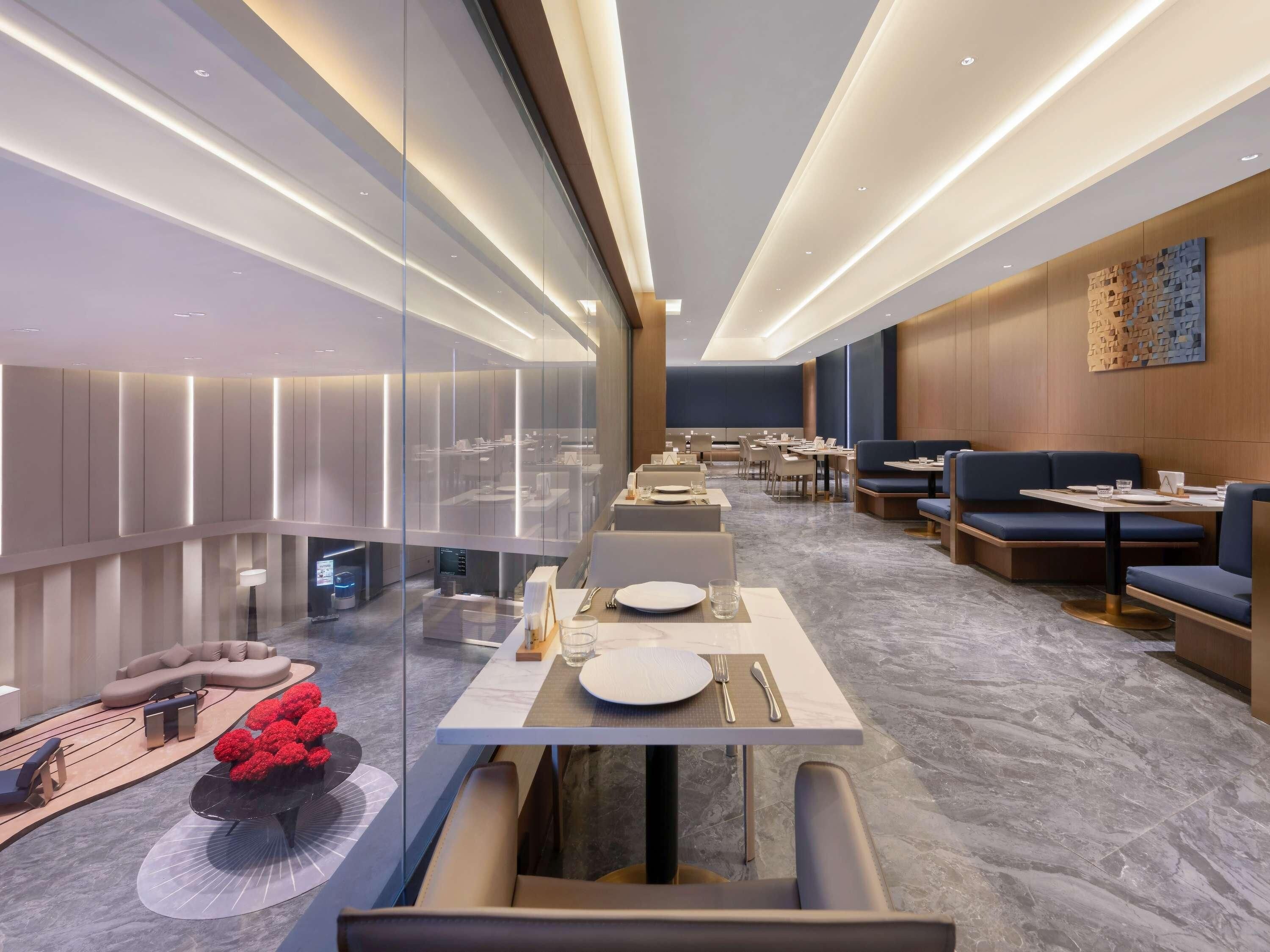 A modern restaurant with a long counter, booths, and a seating area with a view through glass walls.