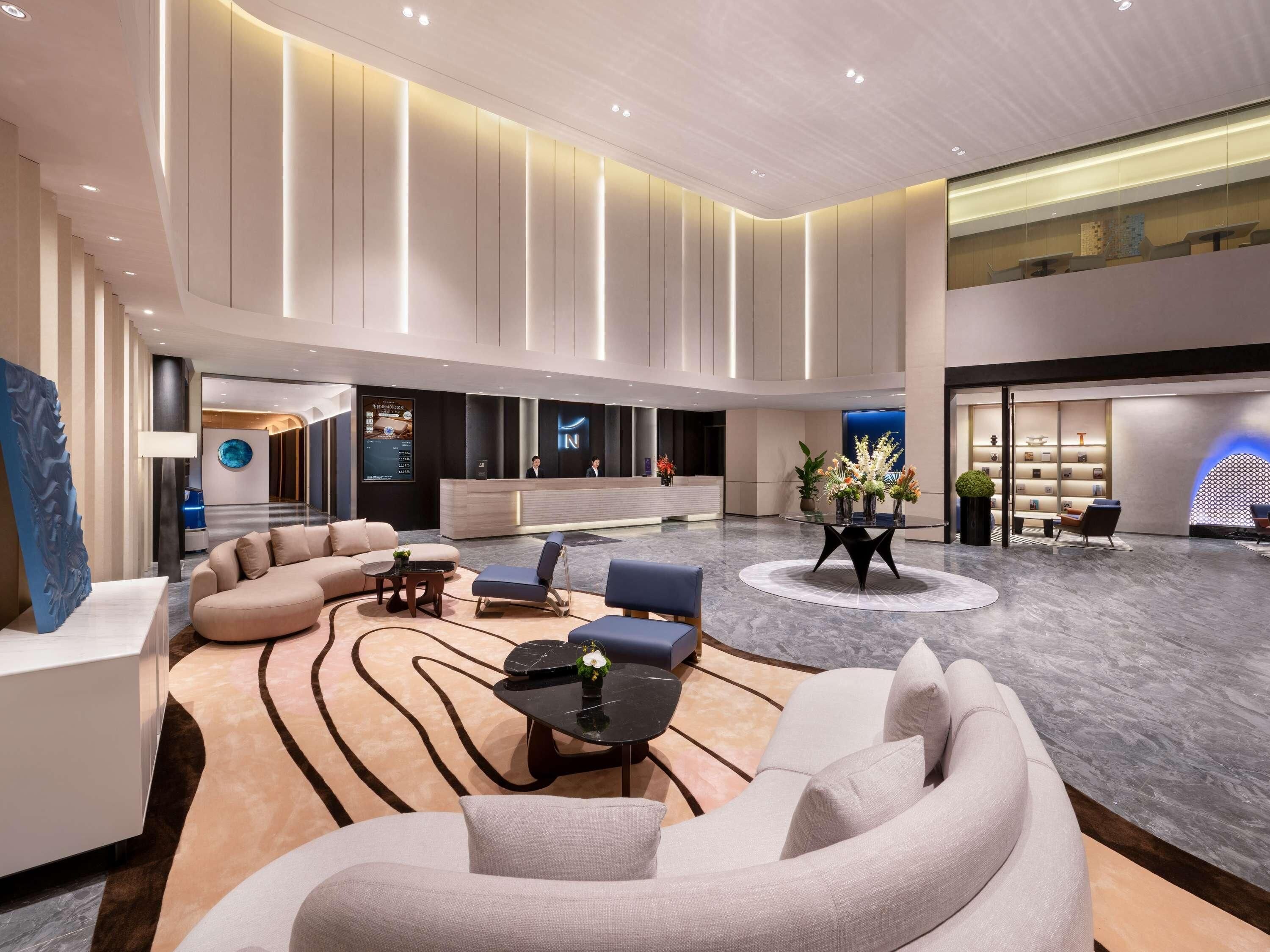 A spacious lobby with a reception desk, seating areas, and a modern interior design.