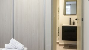 Makuuhuone, jossa on sänky, puinen vaatekaappi ja kylpyhuone, joka näkyy avoimen oven läpi.