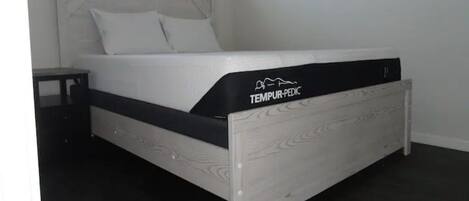 A bed with a white headboard and a black mattress labeled "TEMPUR-PEDIC."