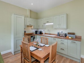 Une cuisine moderne avec des meubles de couleur vert clair, une table à manger en bois et un coin repas pour le petit-déjeuner.