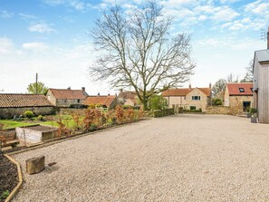 Une propriété rurale avec des maisons en pierre, une allée gravillonnée et un grand arbre.