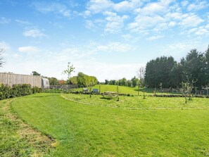 Un paysage rural avec une grange, une table de pique-nique et un espace délimité par une clôture.