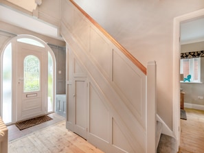 Un escalier avec une rampe en bois et des murs blancs, menant à une pièce dotée d’une fenêtre et d’une porte.