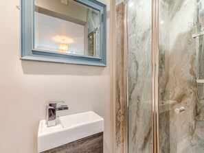 A bathroom with a white sink, a mirror with a blue frame, and a glass shower enclosure.