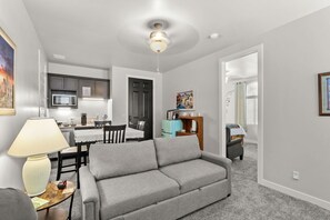A living room with a grey sofa, a dining table, and a kitchen area with a microwave. - New Casita/Suite No cleaning fee. (Las Cruces)