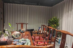 A dining area with a long wooden table, red cushioned chairs, and various decorative items. - Yunshang Shenchu Homestay (Deqing)