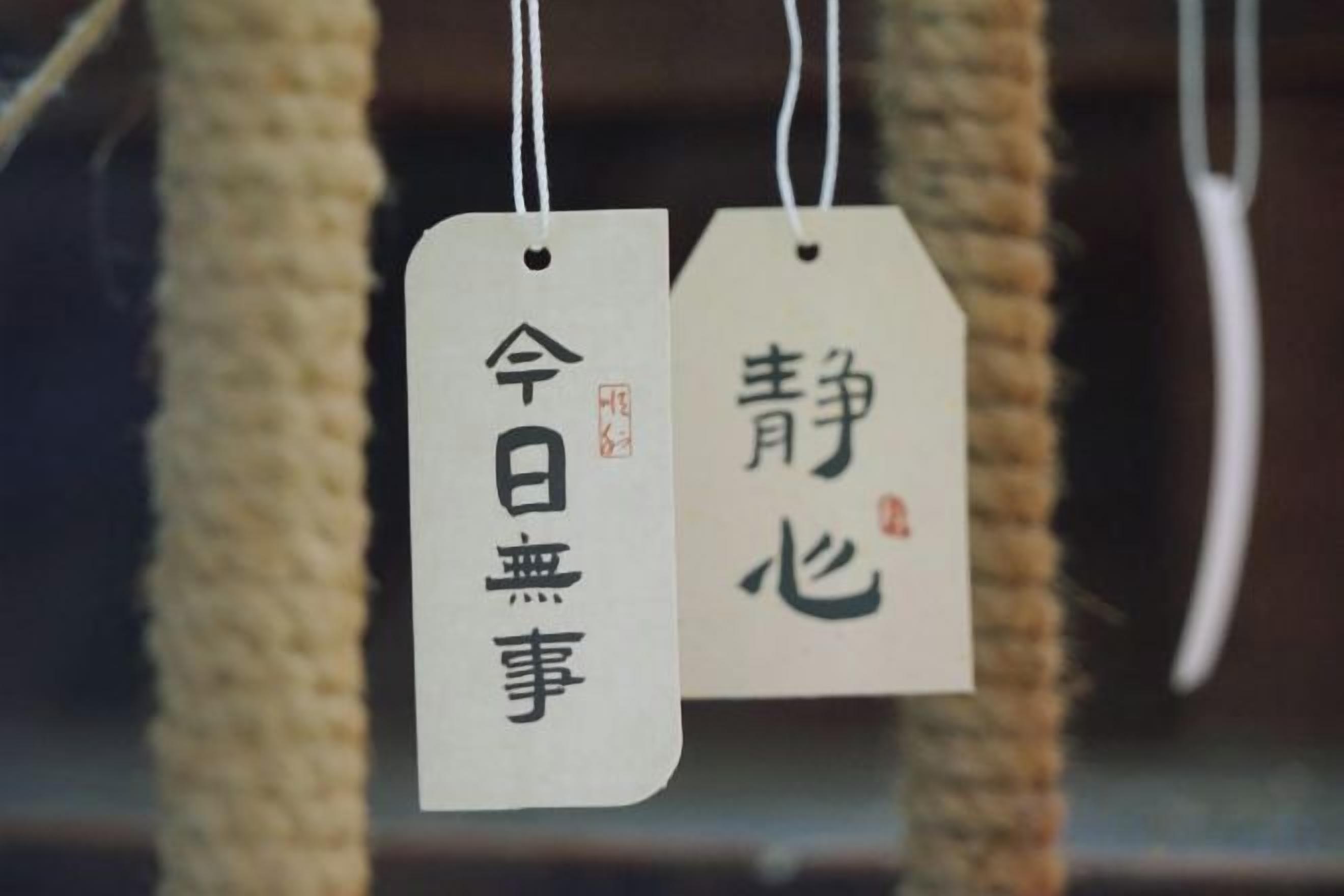 Dos etiquetas con texto japonés, sujetas con una cuerda.