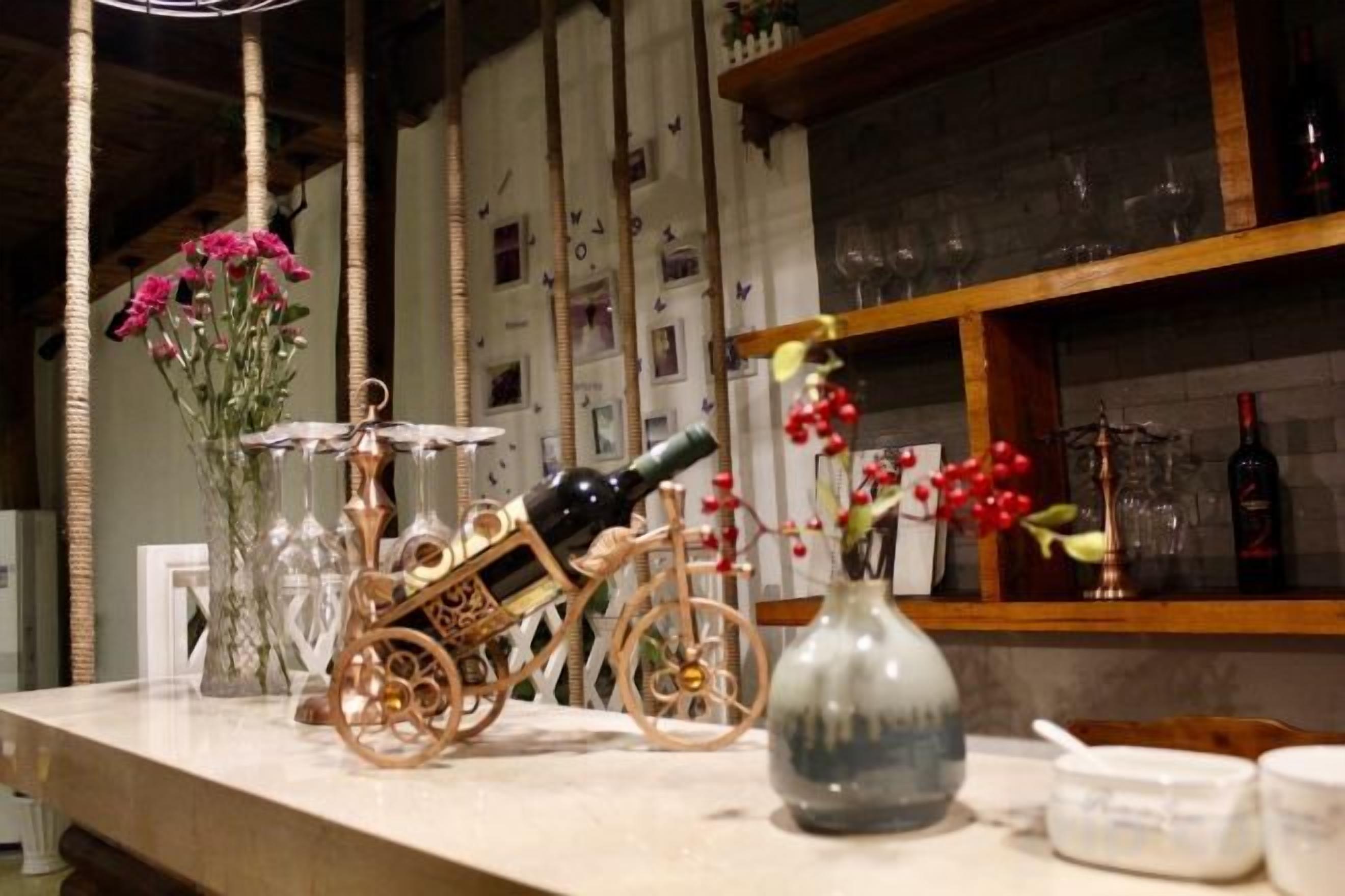 Un rincón de bar con una botella de vino, vasos y una bicicleta decorativa.