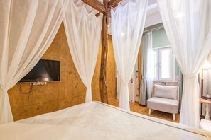 A bedroom with a bed, a TV mounted on the wall, and a window with curtains. - Yunshang Shenchu Homestay (Deqing)