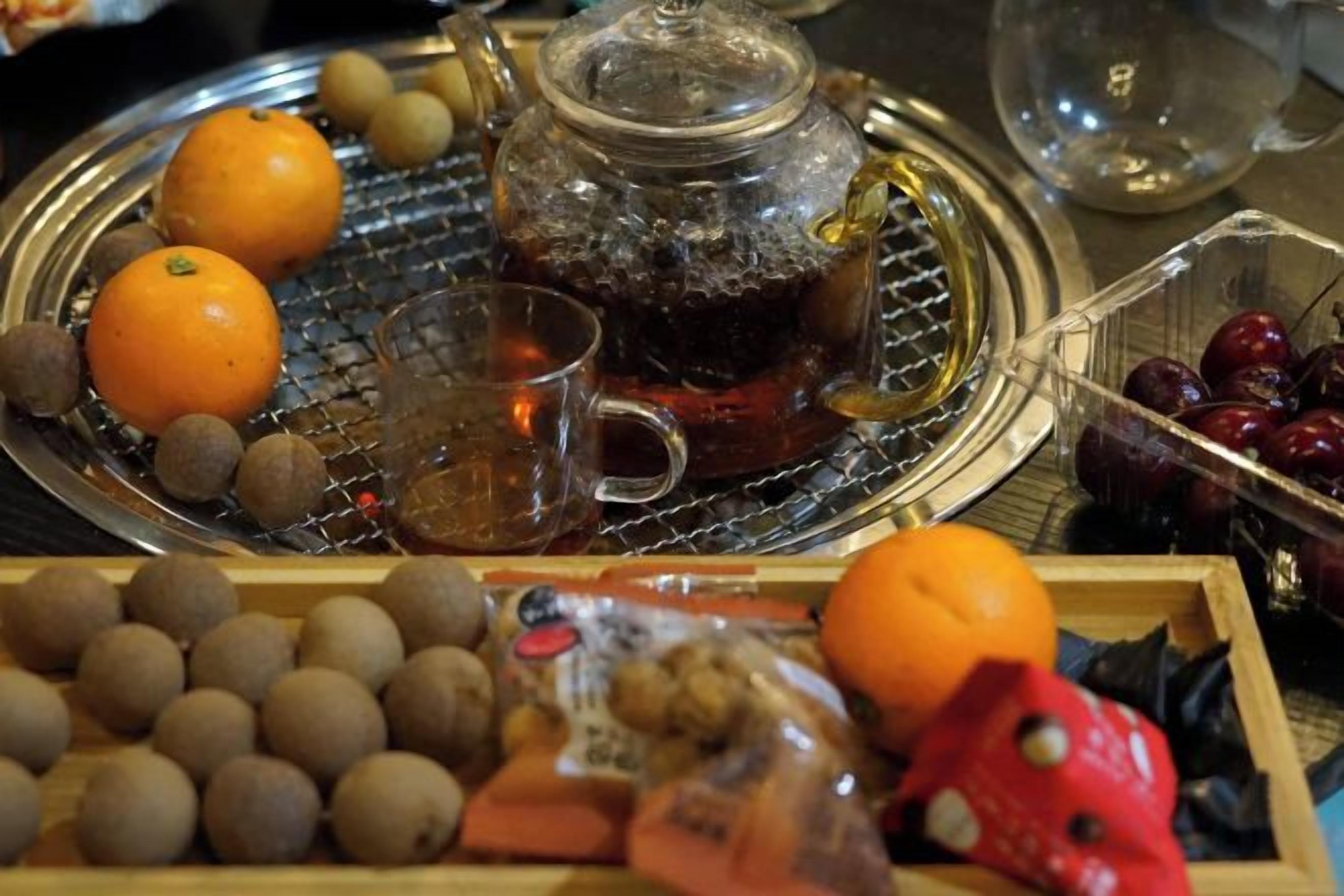 A tray with a teapot, a glass, and various fruits and nuts.