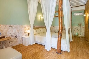 A bedroom with a four-poster bed, a bedside table, a nightstand, and a small round table.