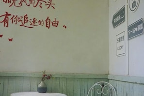 A wall with Chinese text and a small vase with flowers. - Yunshang Shenchu Homestay (Deqing)