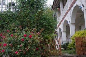 A building with a white facade, multiple arches, and a garden with pink flowers.