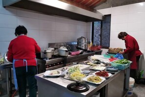 A kitchen with chefs preparing food, a variety of dishes on display, and cooking equipment.