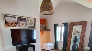 Una camera da letto con un letto, una TV, pavimento in legno, una ventola a soffitto e un grande specchio.