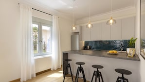 Una cucina moderna con isola centrale, sgabelli da bar, luci a sospensione e vista sull'esterno.
