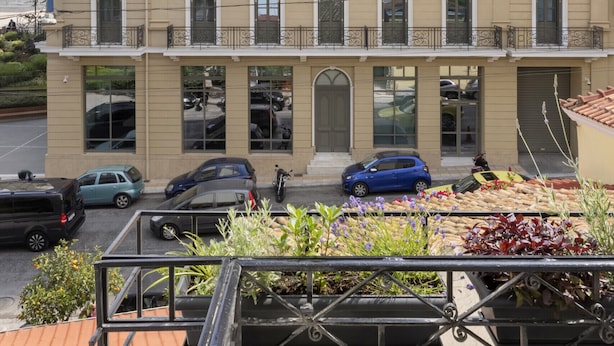 Un edificio a più piani con facciata beige, balconi e un'area di parcheggio antistante.