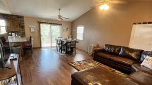 A spacious living area with a dining table, leather sofa, and a ceiling fan. - Cozy Cabin, Less than 1/2 mile to Marina, Boat Trailer Parking (Theodosia)