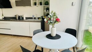 Una cocina moderna con armarios blancos, una mesa redonda de comedor con sillas negras y un florero sobre la mesa.