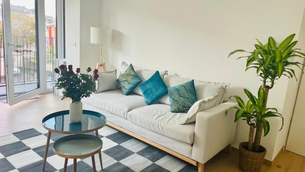 A living room with a sofa, a round coffee table, and two potted plants. - New 1 bedroom in City Center- Terrace (Luxembourg City)