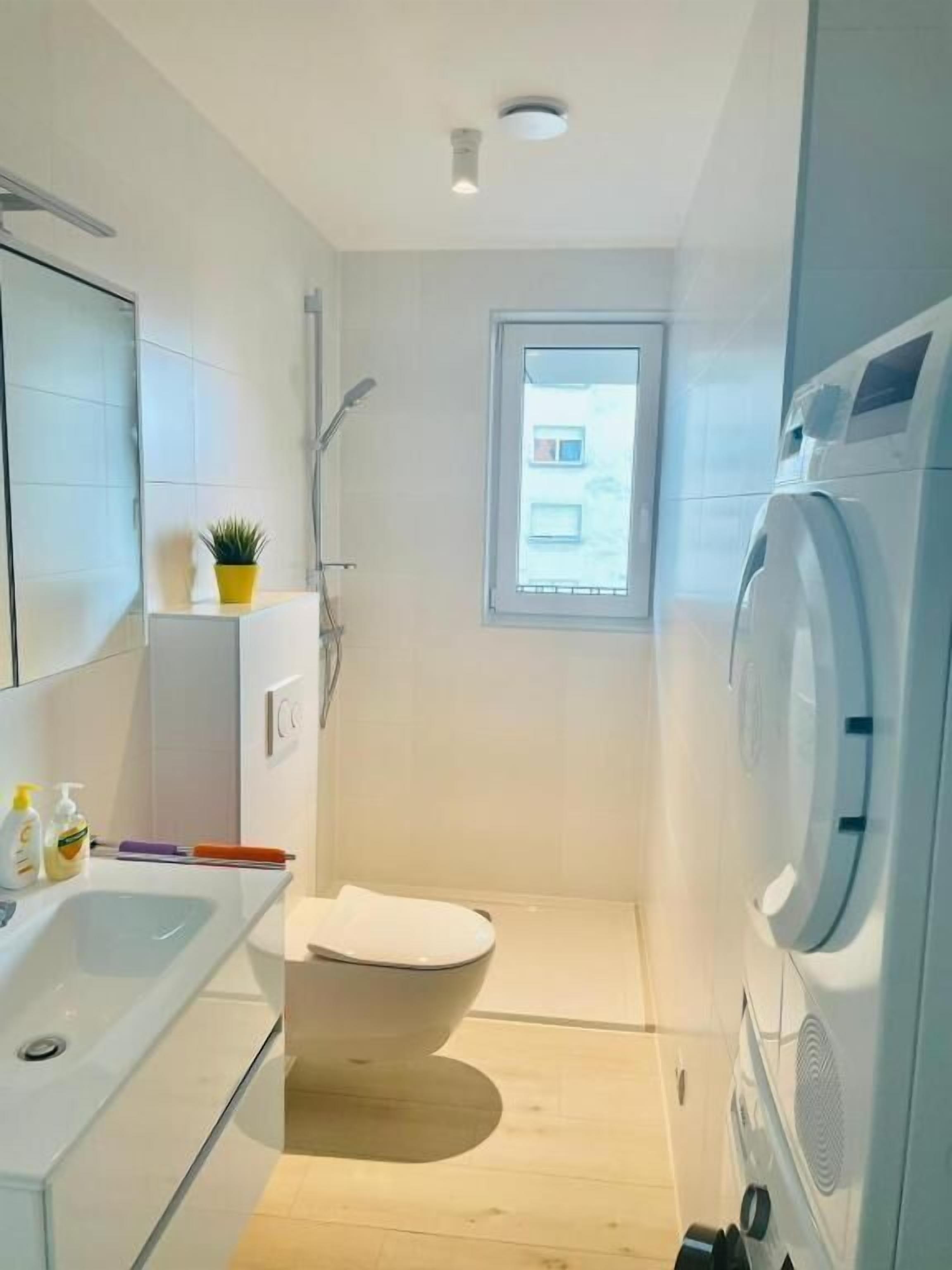 A compact bathroom with a toilet, sink, and a washing machine.