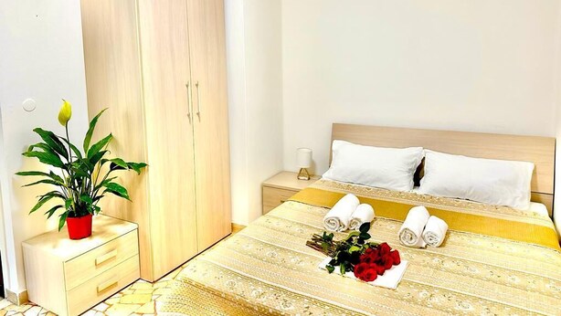 Une chambre d’hôtel avec un lit, une table de chevet, une armoire et une plante en pot.